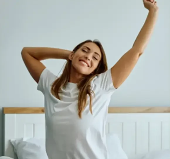 A woman stretching in bed after waking up